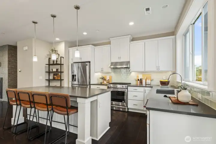 The chef-inspired kitchen showcases a stunning two-tone design, featuring bright, crisp white cabinetry contrasted with elegant, dark quartz countertops, creating a timeless and sophisticated look