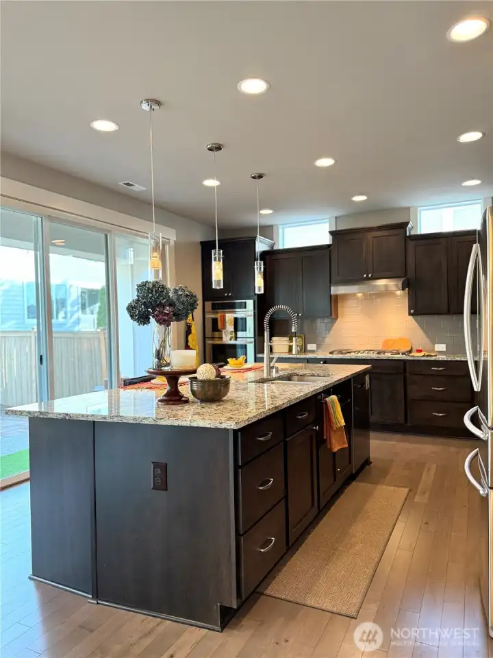 Kitchen with full wall of windows leads to to back patio