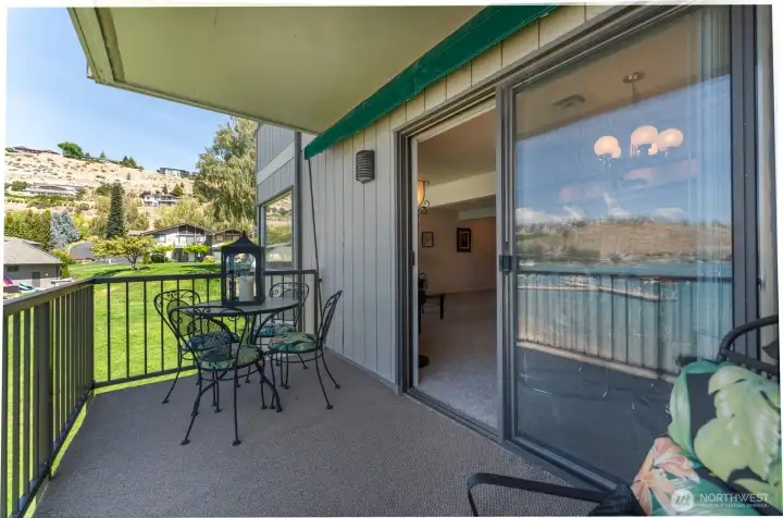 View from deck with sliding glass doors with seating area and dining table.