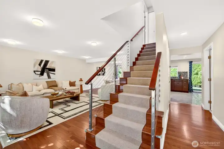 Step inside to an open, light-filled main level showcasing rich hardwood floors that flow seamlessly through both stories. The custom cable-rail staircase with warm wood treads adds architectural interest and a contemporary edge rarely found in homes of this era.
