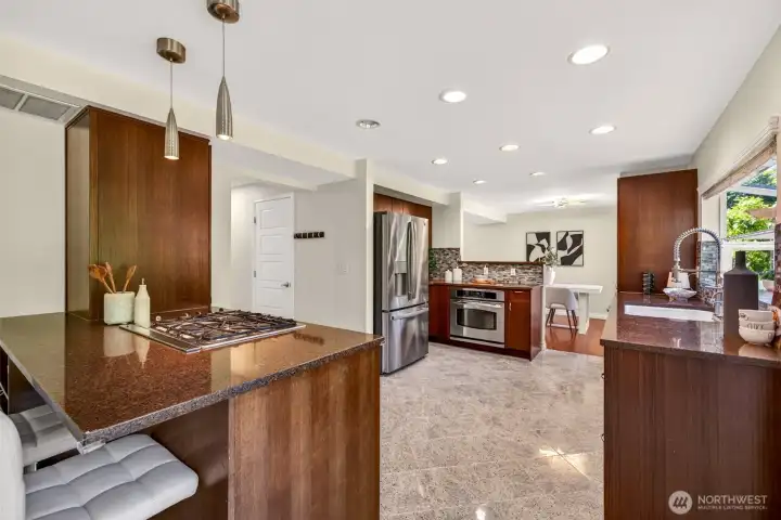 At the heart of the kitchen, a spacious peninsula with built-in gas cooktop creates the perfect spot for casual seating and effortless interaction between cook and guests. The seamless flow from prep area to dining nook makes hosting feel natural, while custom cabinetry and quartz counters keep everything beautifully organized.