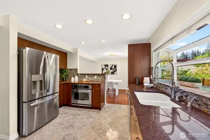A bright corner of the kitchen showcases the artisan glass tile backsplash that catches the light beautifully throughout the day. The stainless French-door refrigerator and built-in wall oven anchor a workspace designed for both serious cooking and easy weeknight meals.