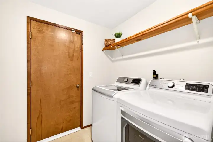 The dedicated main-floor laundry room offers full-size side-by-side appliances and built-in shelving for tidy storage, with direct garage access for easy unloading after errands. A practical layout that makes one of life's daily tasks just a little more efficient.