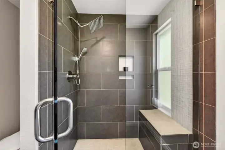 The oversized walk-in tile shower is the showstopper of the primary bath, featuring a luxurious rain head, separate handheld wand, built-in niche, and a generous tile bench for spa-like soaking. It's the kind of daily indulgence that turns the morning routine into a ritual.