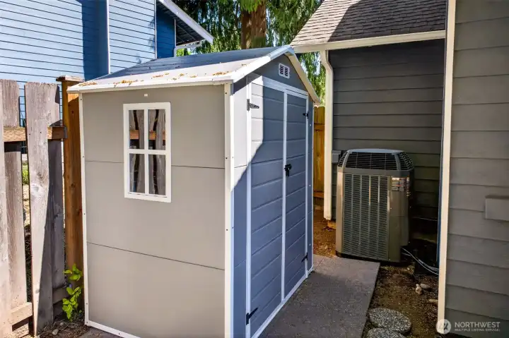 A dedicated outdoor storage shed keeps tools, equipment, and seasonal items tidy and out of the garage, freeing up valuable interior space. The home's efficient heat pump system sits tucked alongside, delivering quiet, year-round central air conditioning and heating.