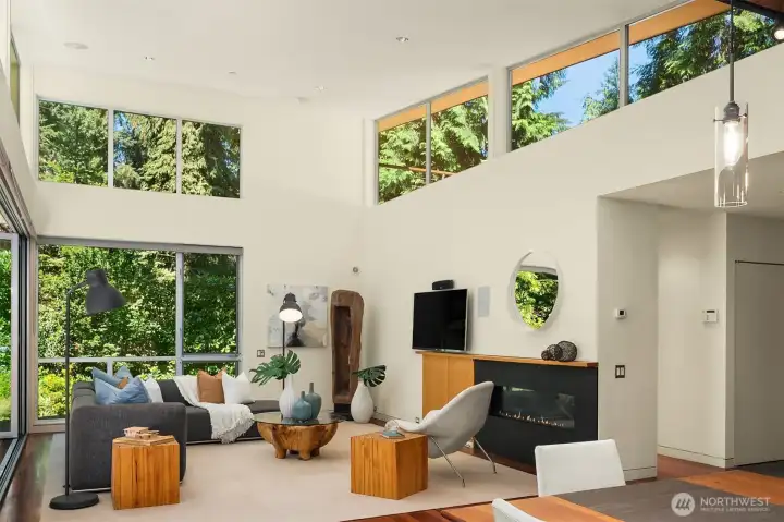 Soaring ceilings and a continuous band of clerestory glass frame the surrounding evergreens from every angle of the living room.