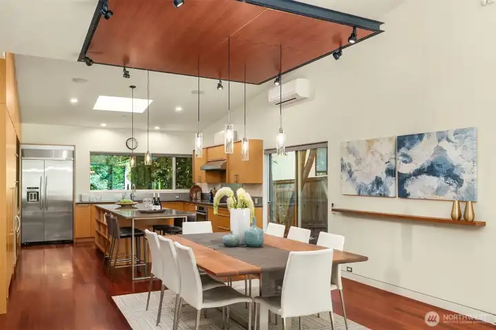 Dining for eight flows directly into the kitchen, where the suspended ceiling plane defines the space without enclosing it.