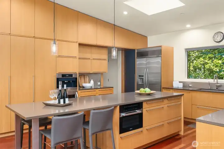 A full wall of floor-to-ceiling fir cabinetry holds the built-in coffee system, wall ovens, and pantry storage, keeping counters clear.