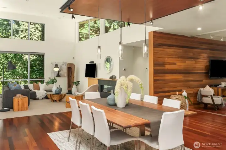 From the dining table, sightlines run past the double-sided hearth wall to the living room and the clerestory glass above.