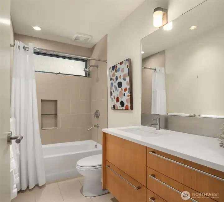 The main floor guest bath with a floating vanity and tiled tub-shower.