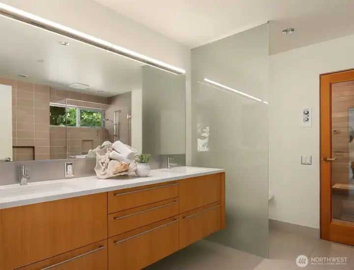 The primary bath pairs a floating double vanity with a frosted glass partition and a cedar-lined sauna just beyond the door.