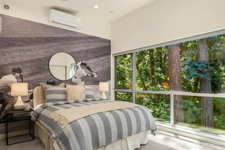 Each upstairs bedroom gets its own wall of glass — this one looks straight into the firs and maples, with a ductless unit for individual climate control.
