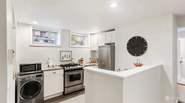 Open and white kitchen with granite counters and in unit washer/dryer combo
