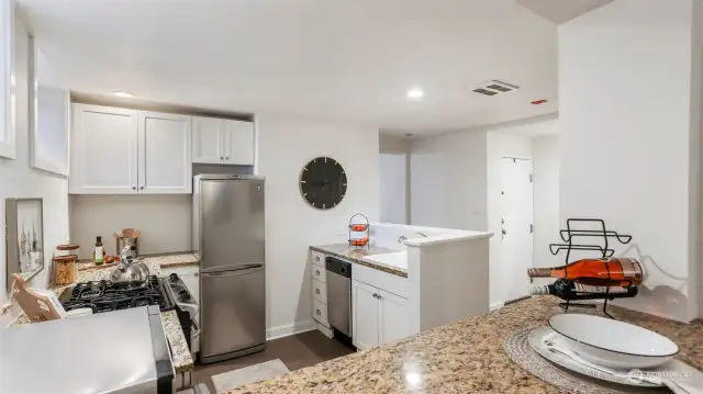 Updated kitchen with granite counters, white cabinets, and stainless steel appliances