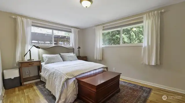 Light and bright primary bedroom with more of the beautiful hardwood flooring.