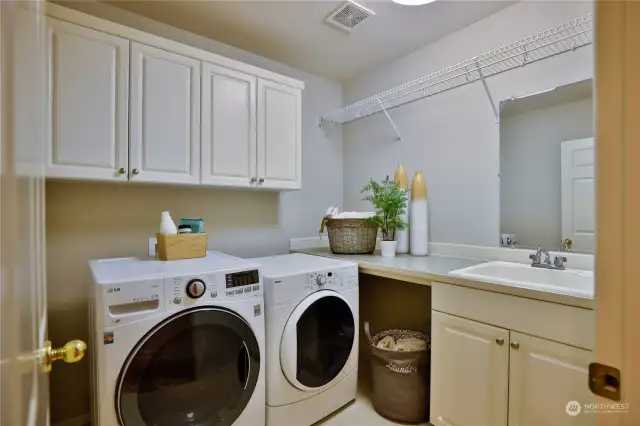 Utility Closet with front-load Washer/Dryer, sink with mirror, and built-in cabinets and shelves