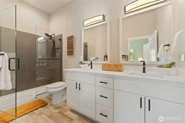 View of the Primary Bathroom w/ double sinks, quartz countertops & an oversized frameless glass & tile shower.
