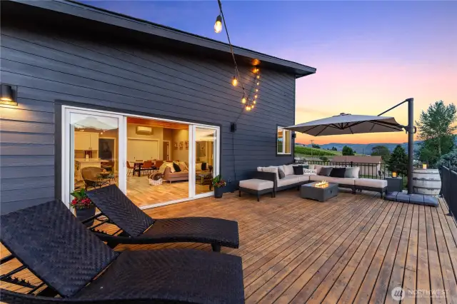 Exterior twilight view of the upper level spacious lake view deck w/ large sliding glass doors off the main living area.