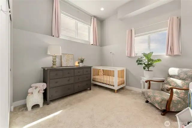 View of the lower level 4th bedroom w/ extra tall ceilings, set up here as a nursery room.