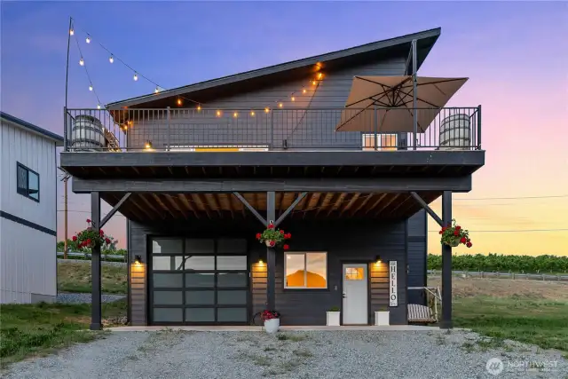 Exterior twilight view of home w/ upper level view deck, garage w/ oversized doors for boat toy storage & ample parking complete w/ 30amp & septic hookups for RV storage.