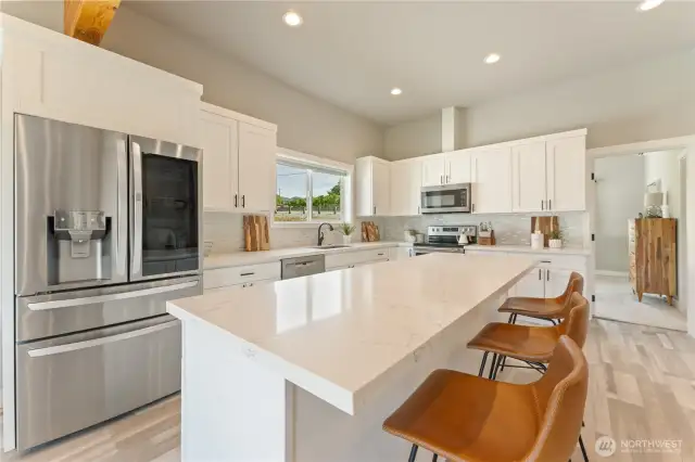 View 1 of kitchen w/ high-end appliances, quartz countertops & sit up bar.