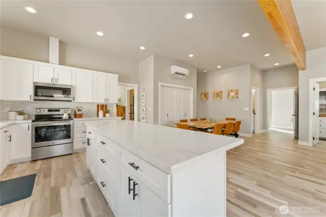 View 3 of kitchen w/ high-end appliances, quartz countertops & sit up bar looking towards the spacious dining room that comfortably seats 8 guests.