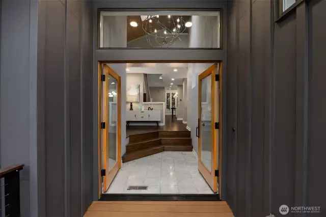The entrance features French doors and an elegant oversized chandelier—setting the tone for modern sophistication throughout.