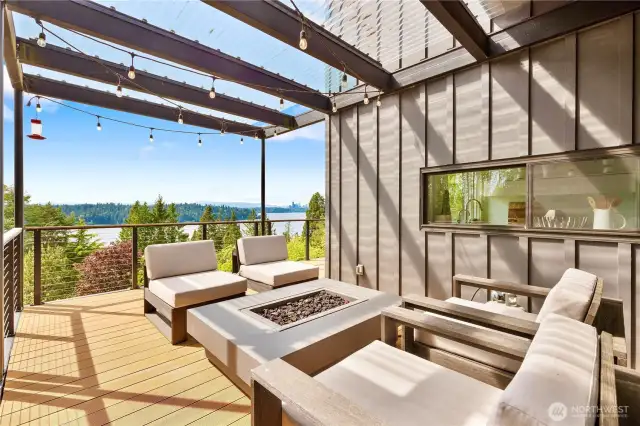 Covered seating area with firepit, conveniently located next to the kitchen and its pass-through window is ideal for cozy, year-round entertaining.