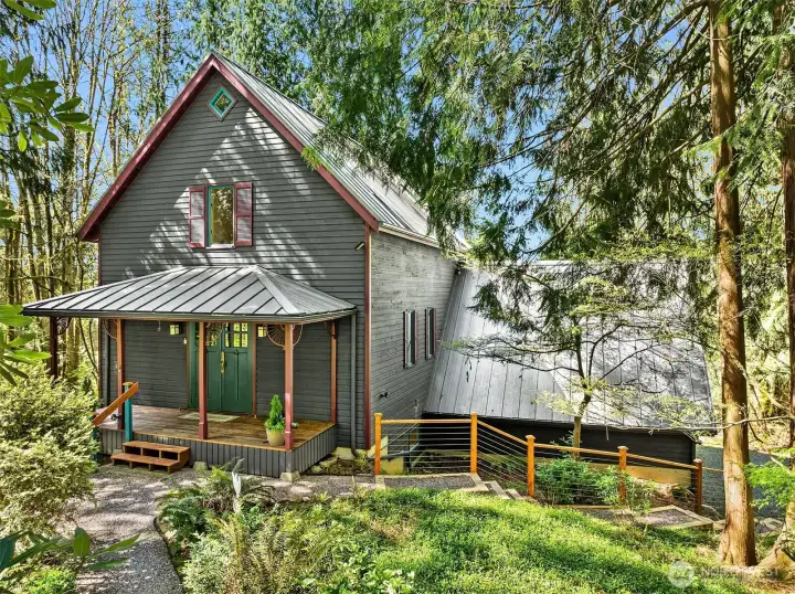 Welcome to your storybook retreat! This GORGEOUS custom home blends timeless architectural details with modern comfort, nestled among lush evergreens for ultimate privacy. The inviting covered porch, rich exterior colors, and custom trim work create instant curb appeal. Inside, light-filled living spaces offer warmth and character, while the wooded surroundings provide a peaceful, park-like setting. Just steps from nature and minutes to town—this home is the perfect blend of seclusion and convenience.