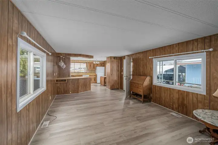 Looking from N end of living room back to kitchen and entrance door. Lots of large bright windows