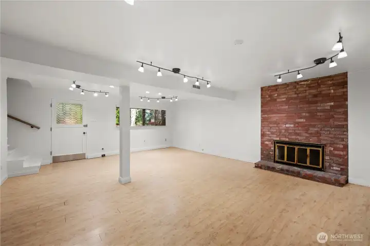 Lower level: bright rec room, backyard access, beautiful brick fireplace, high ceilings, lots of natural light & 1 bed/1 bath. The door leads out to the large fully fenced, level backyard w/ oversized patio.