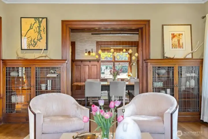 Wide openings between rooms creates a more casual, modern feel. Original leaded glass bookcases flank the opening to the dining room.