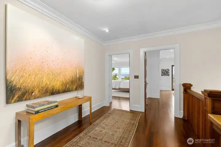 The hallway with gallery scaled walls leads to the primary  suite.
