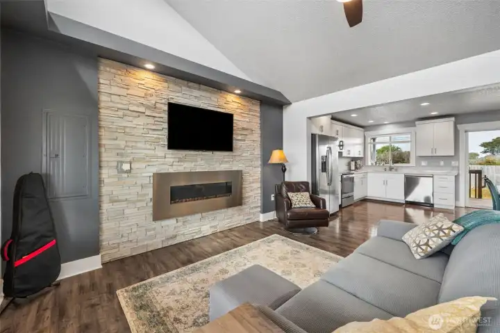 The living room has a vaulted ceiling with a ceiling fan and plenty of windows providing natural light. Rock wall accent (electric fireplace isn't functioning). Laminate floors make tidying up a breeze!