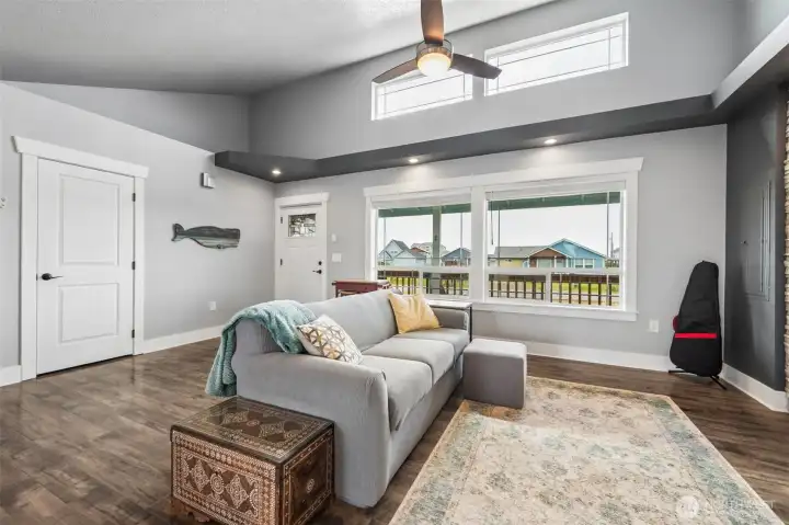 The living room vaulted ceiling with windows higher up allowing the natural light to flood this space. There are built-in shelving areas up high that you may display your treasures or leave unfilled. The flooring is wood laminate.