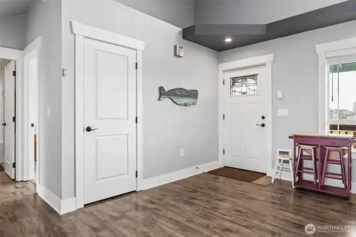 Closer look at the entry to the right, center door is a closet, hallway to the left leads to the primary suite, secondary bedroom and hallway full bathroom.