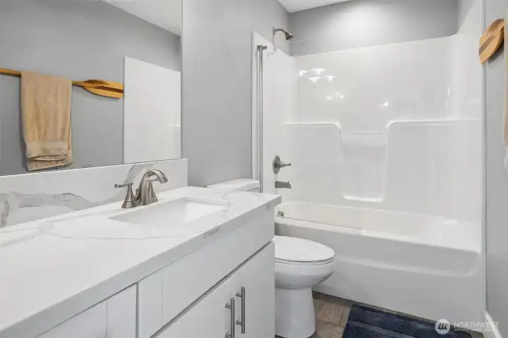 This is the main bathroom for this home. It's a full bathroom with a large vanity with quartz countertop, tub & shower combo with a glass shower splash guard.