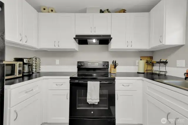 Modern kitchen with black appliances and counter tops.