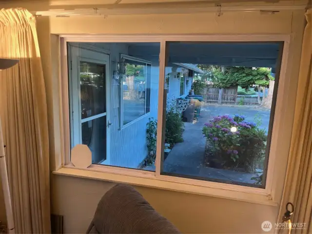 Family room looks out to garden, front entry, and driveway. Curtains can be closed for privacy.