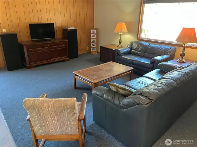 Lots of room for couches and entertainment center and exercise equipment. Wood panel walls. Attic stairway here leads to lots of storage above.