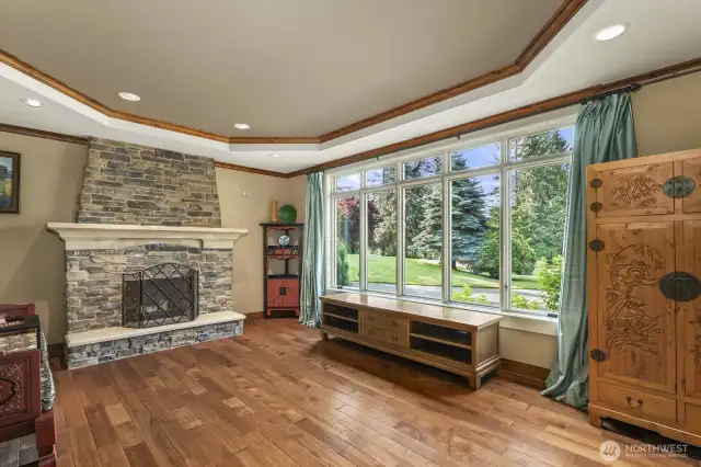 Formal living room with double crown molding, stone surround masonry fireplace with raised hearth and hardwood floors.