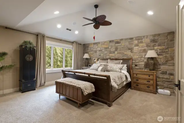 The tranquil primary suite with a stone bed wall.