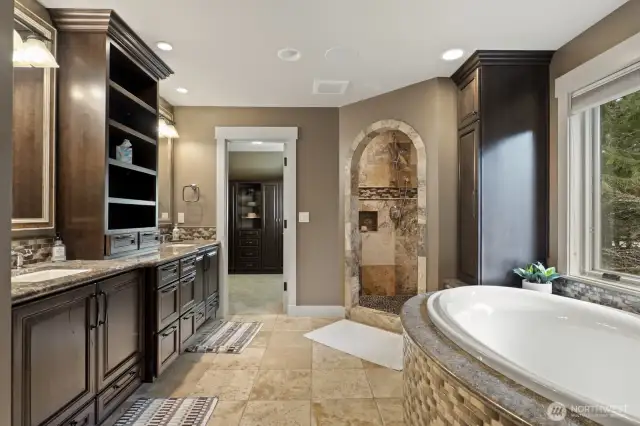 The primary bathroom with air jetted soaking tub, travertine surfaces and floors and large walk-in closet.
