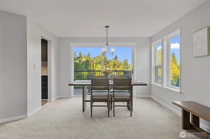 The dining space is filled with natural light from surrounding windows and opens to the deck, creating seamless indoor-outdoor living.