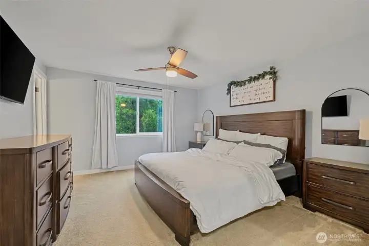 The primary suite features a walk in closet, ceiling fan, and a large window overlooking the greenery - a peaceful retreat at the end of the day.