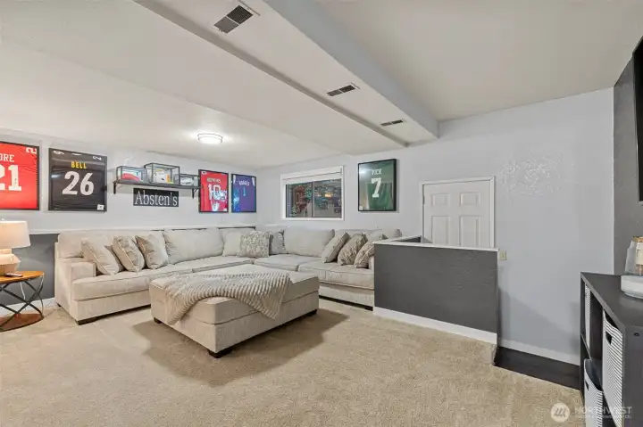 A versatile open space on the lower level provides options for a home office, workout room, playroom, or second living area with stylish lighting and neutral finishes ready to fit your lifestyle.
