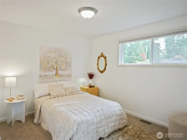 Cozy bedroom with large window, soft bedding, and elegant decor.
