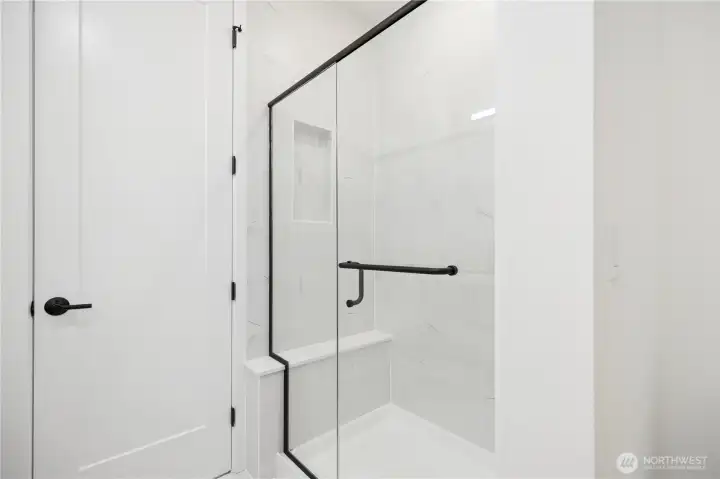 Primary bath featuring tiled shower with seat.