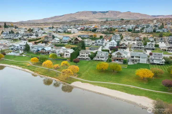 Scenic aerial highlighting the shoreline path, sandy beach, and surrounding waterfront homes within the Sun Cove community.