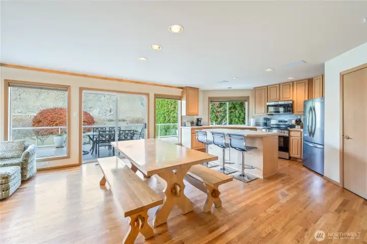 Light-filled dining area and kitchen featuring stainless steel appliances, bar seating, and sliding doors leading to the deck.